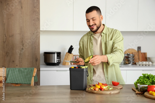Papier peint Young man with compost bin and vegetable scraps during cooking in kitchen