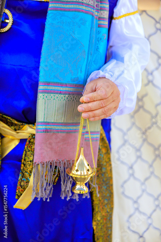 Canvas Print Jewish high priest in vibrant traditional attire holds brass incense burner in festive during Jew holy cultural event