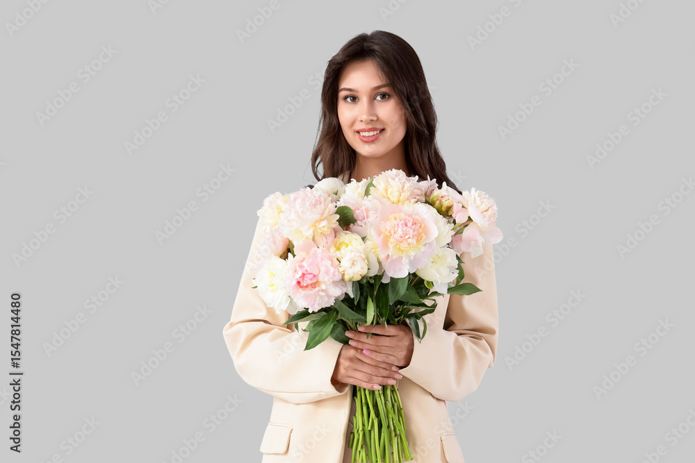 Young woman in jacket with peony flowers on light background Young woman in jacket with peony flowers on light background