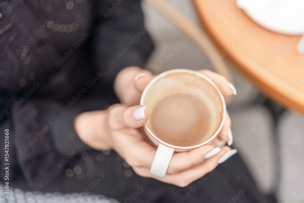 Coffee Cup Hands Relaxation: Lady holds latte outside cafe table in daytime for relaxation, drink, break. Coffee Cup Hands Relaxation: Lady holds latte outside cafe table in daytime for relaxation, drink, break.