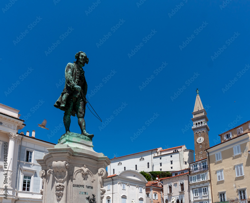 Fototapeta premium A vibrant, low-angle shot captures the iconic bronze statue of Giuseppe Tartini, the famous composer and violinist, standing prominently in Tartini Square, Piran, Slovenia