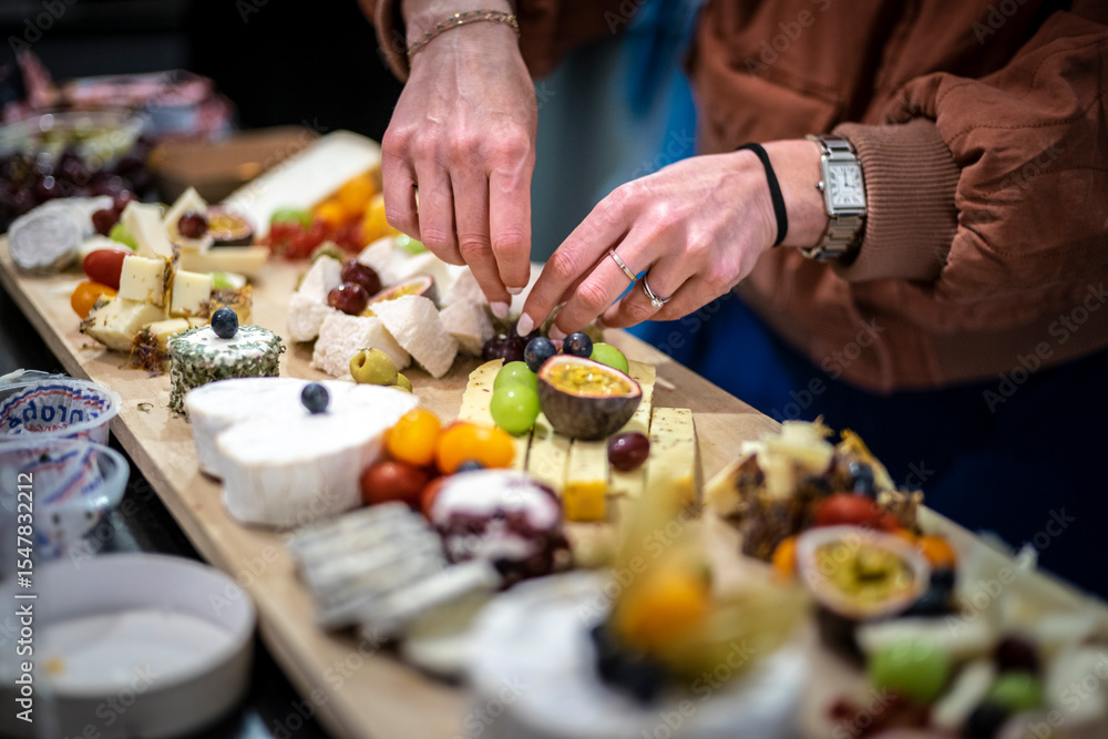 Naklejka premium Hands Arranging a French Cheeses and Fruit Platter. assortment of french cheeses