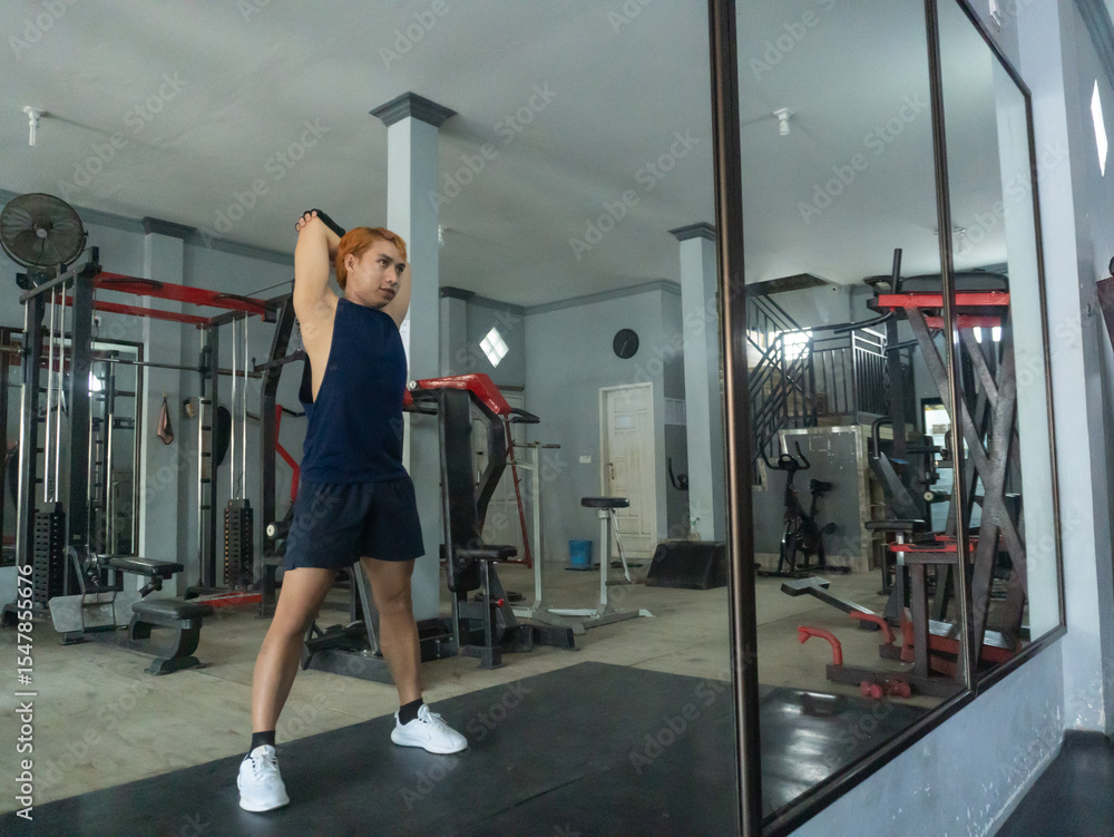 Fototapeta premium Gym, asian indonesian man stretching legs for warm up, workout motivation and fitness mindset for workout with hands on feet. Focus, commitment and male athlete on the floor to stretch in sports club 