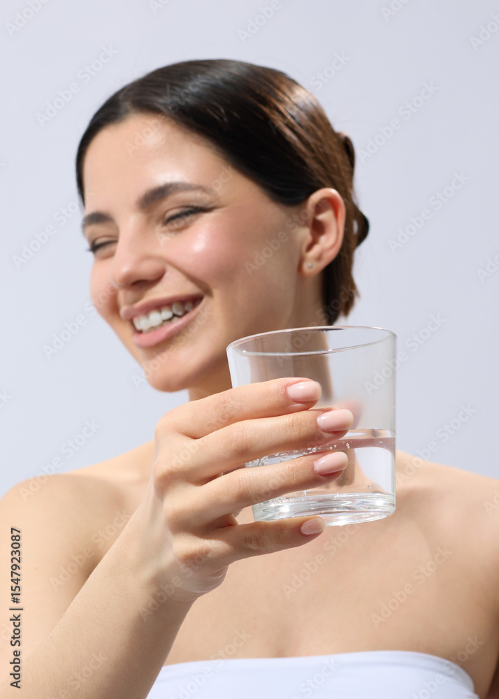 A brunette woman drinks water from a glass cup A brunette woman drinks water from a glass cup