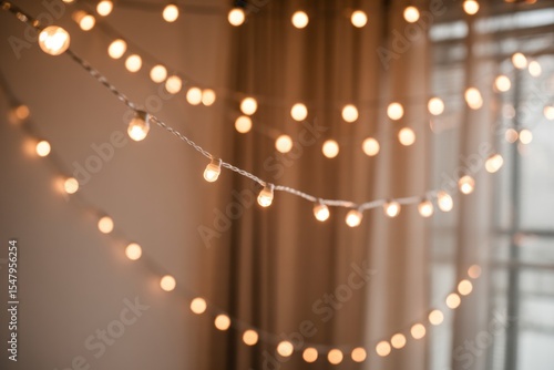 Warm toned blurred string lights against beige curtains and wall