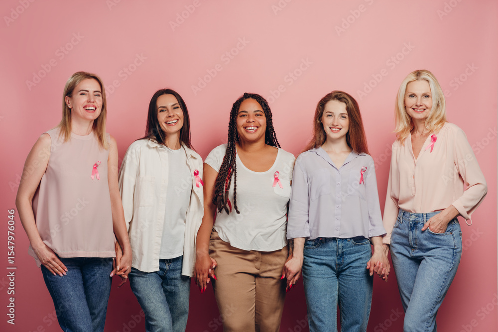 Diverse women holding hands showing pink ribbons for breast cancer awareness Diverse women holding hands showing pink ribbons for breast cancer awareness