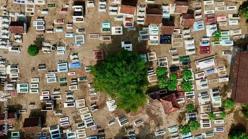 Overhead aerial view of a densely packed traditional Indonesian cemetery with colorful graves and a central green tree