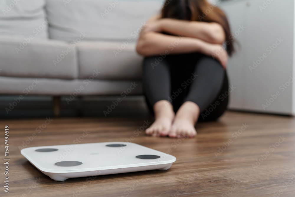 Fototapeta premium Sad woman with fat upset bored of dieting Weight loss fail Fat diet and scale sad asian woman on weight scale at home weight control