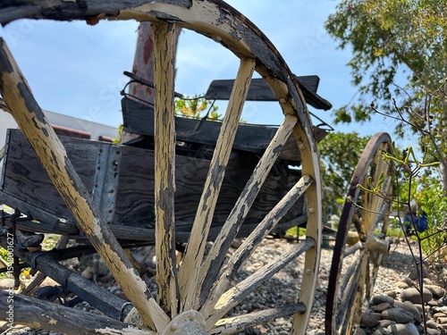 A close-up detail of a weathered, rustic wagon wheel in San Marcos, California, highlighting its aged wood and metal textures, and vintage craftsmanship.