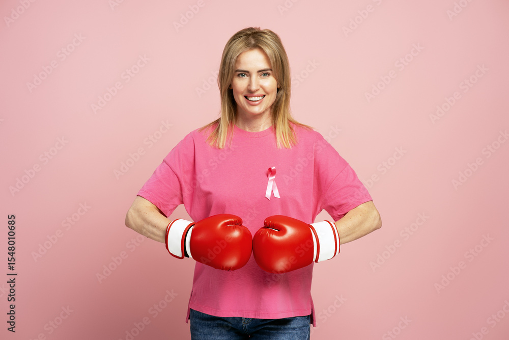 Smiling, beautiful woman wearing boxing gloves and pink ribbon supporting breast cancer awareness Smiling, beautiful woman wearing boxing gloves and pink ribbon supporting breast cancer awareness
