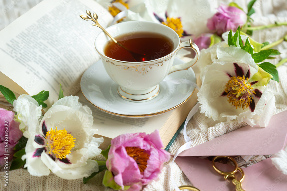 Peony flowers and a cup of tea, books on a white blanket. Peony flowers and a cup of tea, books on a white blanket.