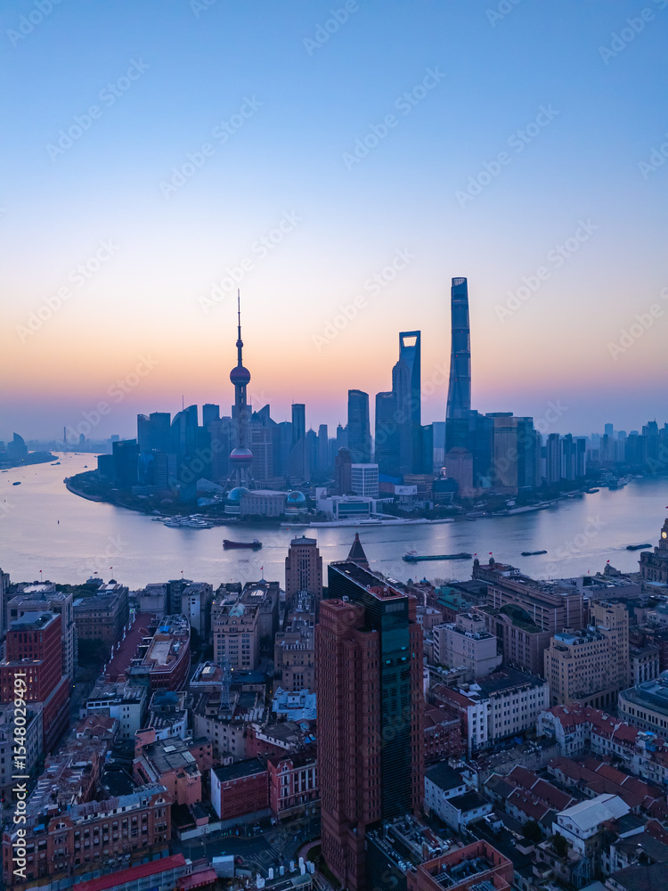 Obraz premium Aerial view of Shanghai skyline with winding river at sunrise.