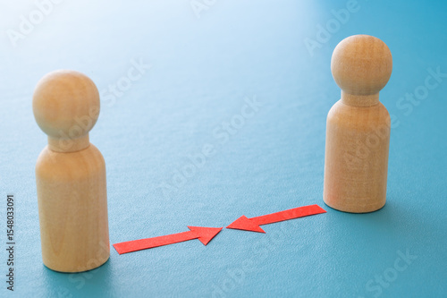 Concept of conflict I war between people or groups. Wooden figures gathered in two groups facing each other.