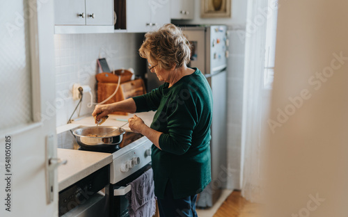 Photography An elderly woman is preparing a meal in a warm, homey kitchen setting with attention to detail