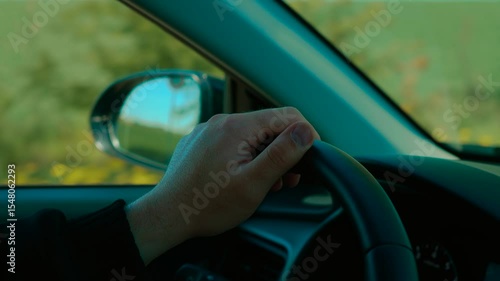 Wallpaper Mural Hand holding steering wheel while unrecognizable man driving past green field. Male steering vehicle, maintaining control on countryside road. Driver cruising calmly, hand gripping wheel on scenic Torontodigital.ca
