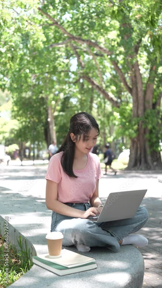 Young woman sitting on grass using laptop in park Young woman sitting on grass using laptop in park