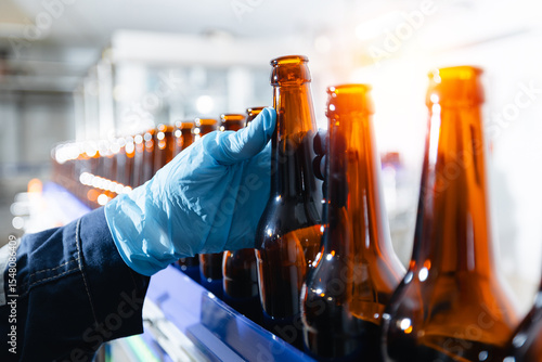 Automated beer bottling process in brewery factory. Worker quality control on food industry