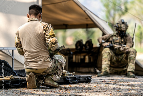 Картината върху платно Special forces soldiers preparing tactical gear at military field base camp with weapons and equipment during outdoor training operation