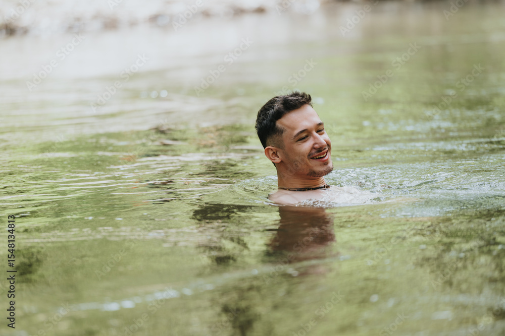 Fototapeta premium A young man happily swims in a serene river, surrounded by lush nature and sunlight. The image evokes relaxation, enjoyment, and connection with the outdoors.