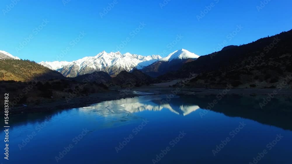 Snow capped mountains reflected in a pristine blue lake Snow capped mountains reflected in a pristine blue lake
