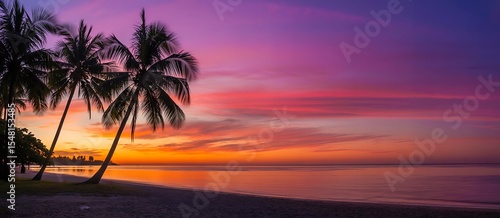 Fototapeta Naklejka Na Ścianę i Meble -  Tropical beach scene with palm trees silhouetted against a vibrant sunset sky and ocean