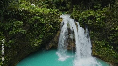 Slow mo Close-Up of Twin Waterfalls at Kawasan Falls Pouring into a Turquoise Pool Surrounded by Mossy Cliffs and Tropical Greenery. Cebu, Philippines.