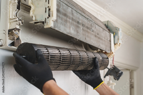 Technician Removing Blower Fan from Wall-Mounted Air Conditioner Unit