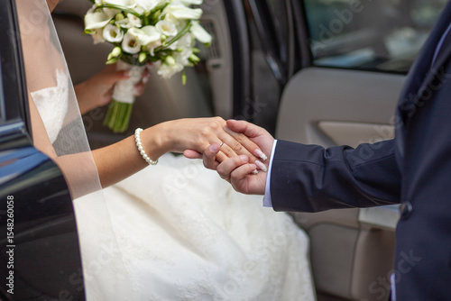 Bride and Groom Holding Hands by Wedding Car