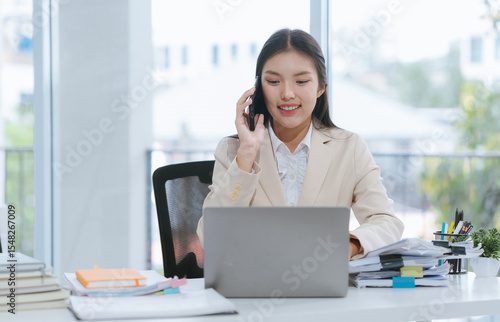 Asian Woman Working in Office with Laptop and Phone