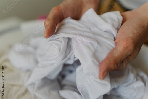 фотографія Detail cropped shot of unrecognizable man soaking white clothes in basin, preparing for washing while ensuring cleanliness and hygiene at home