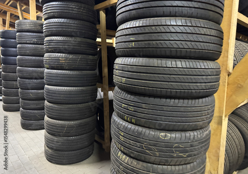 Rows of used tires are organized on wooden shelves in a warehouse, showcasing a clean and efficient storage method. The bright lighting highlights the tire patterns