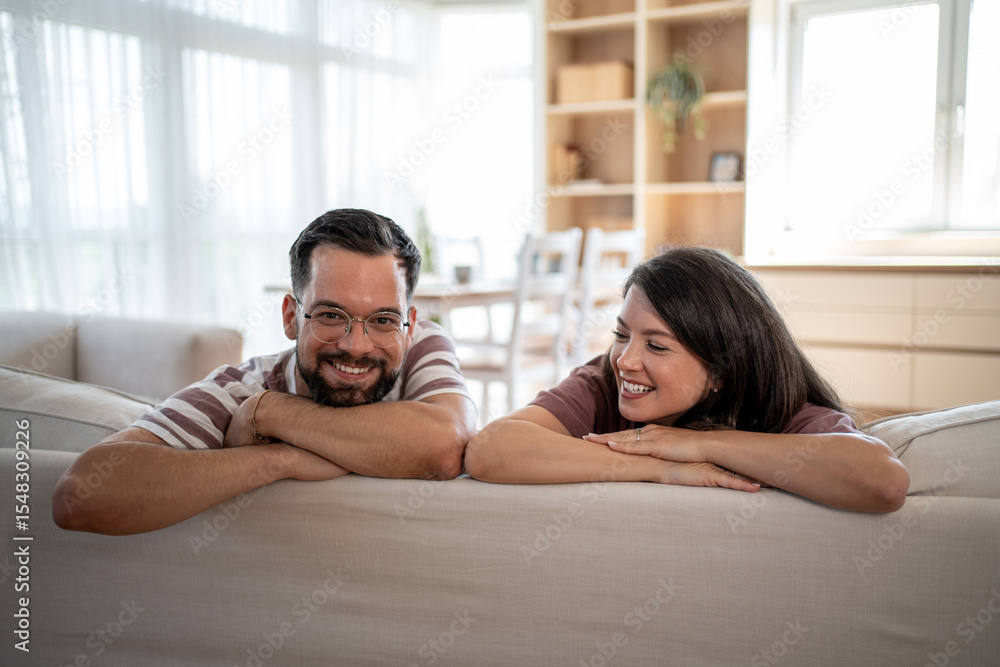 Fototapeta premium Happy couple relaxing on sofa, enjoying time together at home