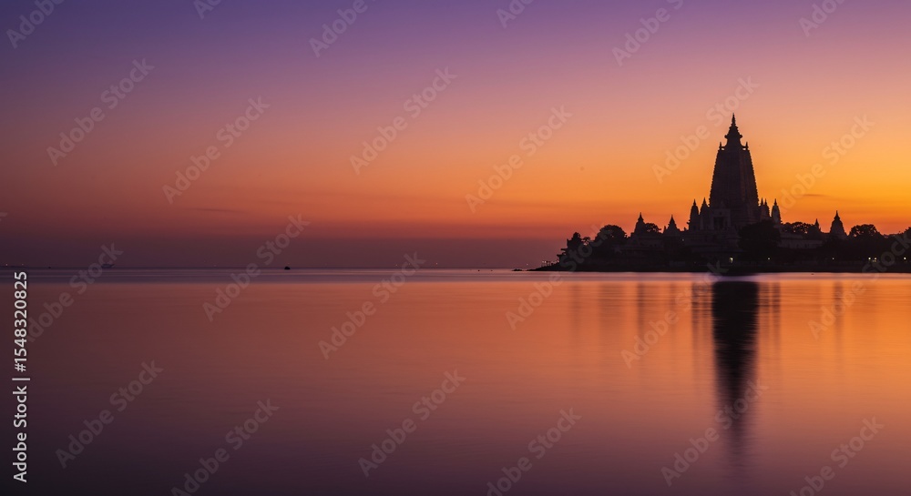 Fototapeta premium Ancient Riverside Temple Silhouetted at Sunset with Reflecting Water and Golden Sky – Peaceful Historical Landmark in South Asia for Travel, Culture, and Landscape Concepts