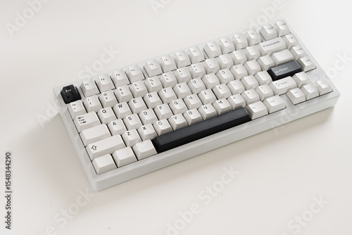 Modern mechanical keyboard on white desk as background. Minimal style and design keyboard. Custom build keyboard with black and white cap. Close up