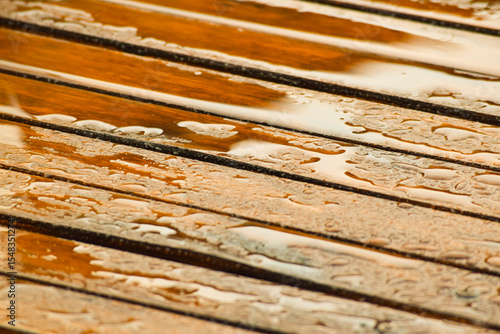 Vista parcial de mesa de listones de madera con gotas de lluvia
