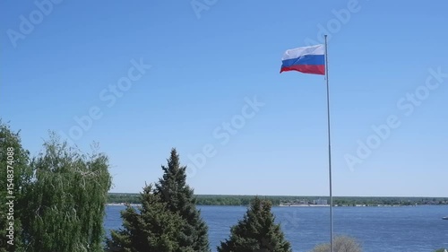 Large flag of the Russian Federation on a flagpole against a blue sky. Close up