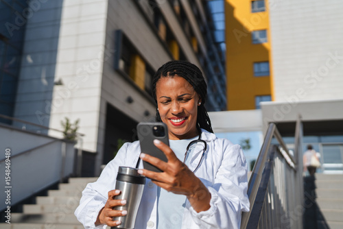 Papier peint african american woman doctor on break use cellphone in front hospital