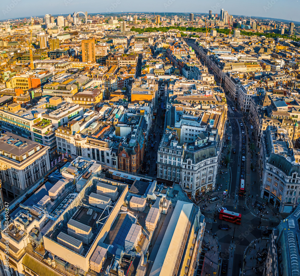 Fototapeta premium Aerial view of Regent Street in London with its sweeping curve, elegant architecture, red buses, and busy city streets on a clear day.