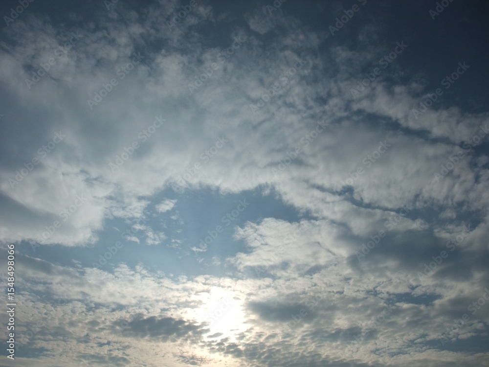 Obraz premium Expansive sky filled with fluffy clouds and soft sunlight peeking through, creating a serene atmosphere, ideal for backgrounds or nature-themed projects with copy space