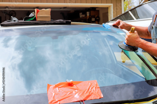 Bild auf Leinwand Windshield repair process underway in garage, applying adhesive tools during rep