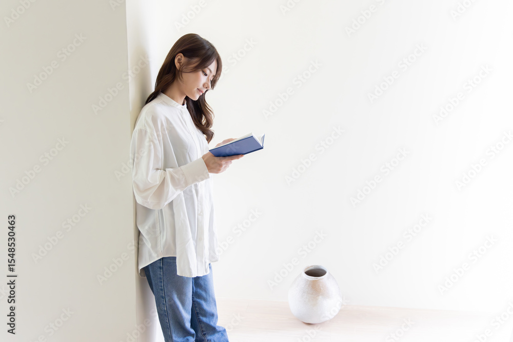 Fototapeta premium 壁にもたれて読書する女性