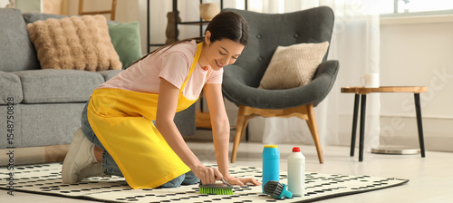 Young woman cleaning carpet...