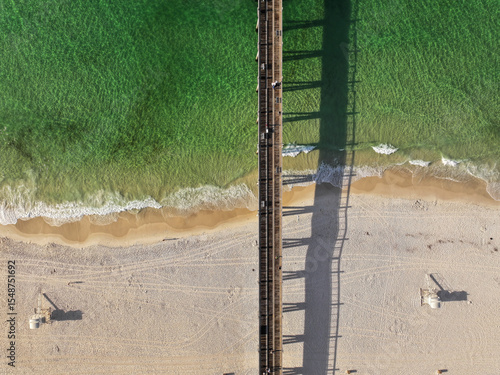 Pensacola Beach Gulf Pier is a fishing pier in Escambia County, Florida looking down at waves crashing in on the shore.
