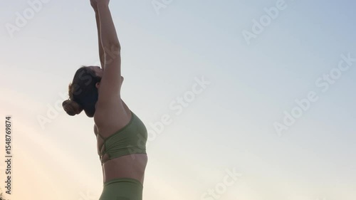 Woman stretching arms upwards on beach during yoga practice