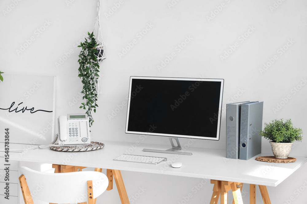 Blank computer monitor with telephone on table in light office Blank computer monitor with telephone on table in light office