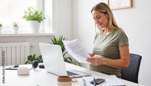 Pregnant woman reading documents while sitting at desk in home office  