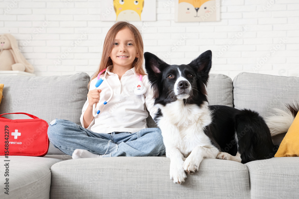 Cute little girl with toy stethoscope and dog on sofa at home Cute little girl with toy stethoscope and dog on sofa at home