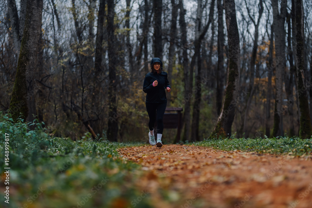 Young sportswoman running in forest during autumn Young sportswoman running in forest during autumn