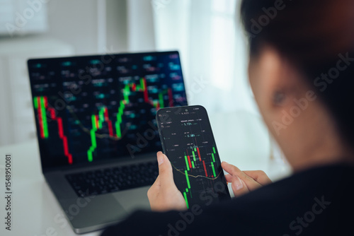 Tableau sur toile An investor monitors real-time stock market data on a smartphone and laptop, analyzing charts, financial trends, and cryptocurrency for informed trading decisions in a digital workspace
