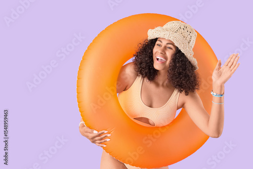 Foto Young African-American woman in swimsuit with orange inflatable ring waving hand